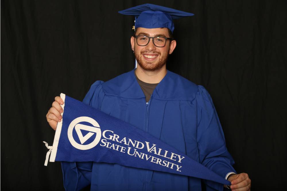 graduating student with grand valley state university flag